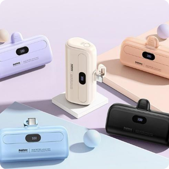 Mini portable power bank with built-in connector available in pastel purple, cream, pink, light blue, and black with digital battery displays.